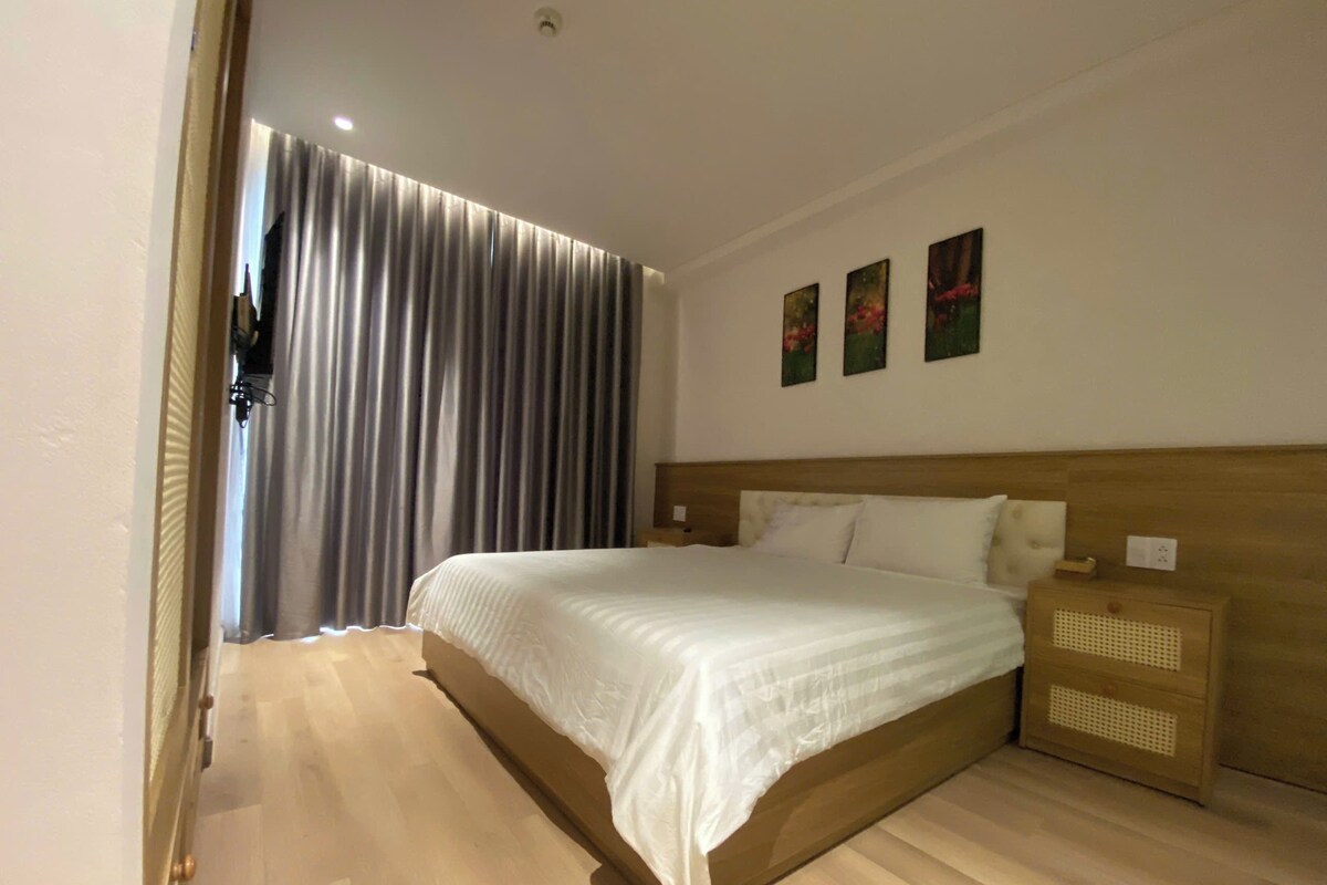 Een hotelkamer met een houten bed, een nachtkastje en een aan de muur bevestigde televisie.