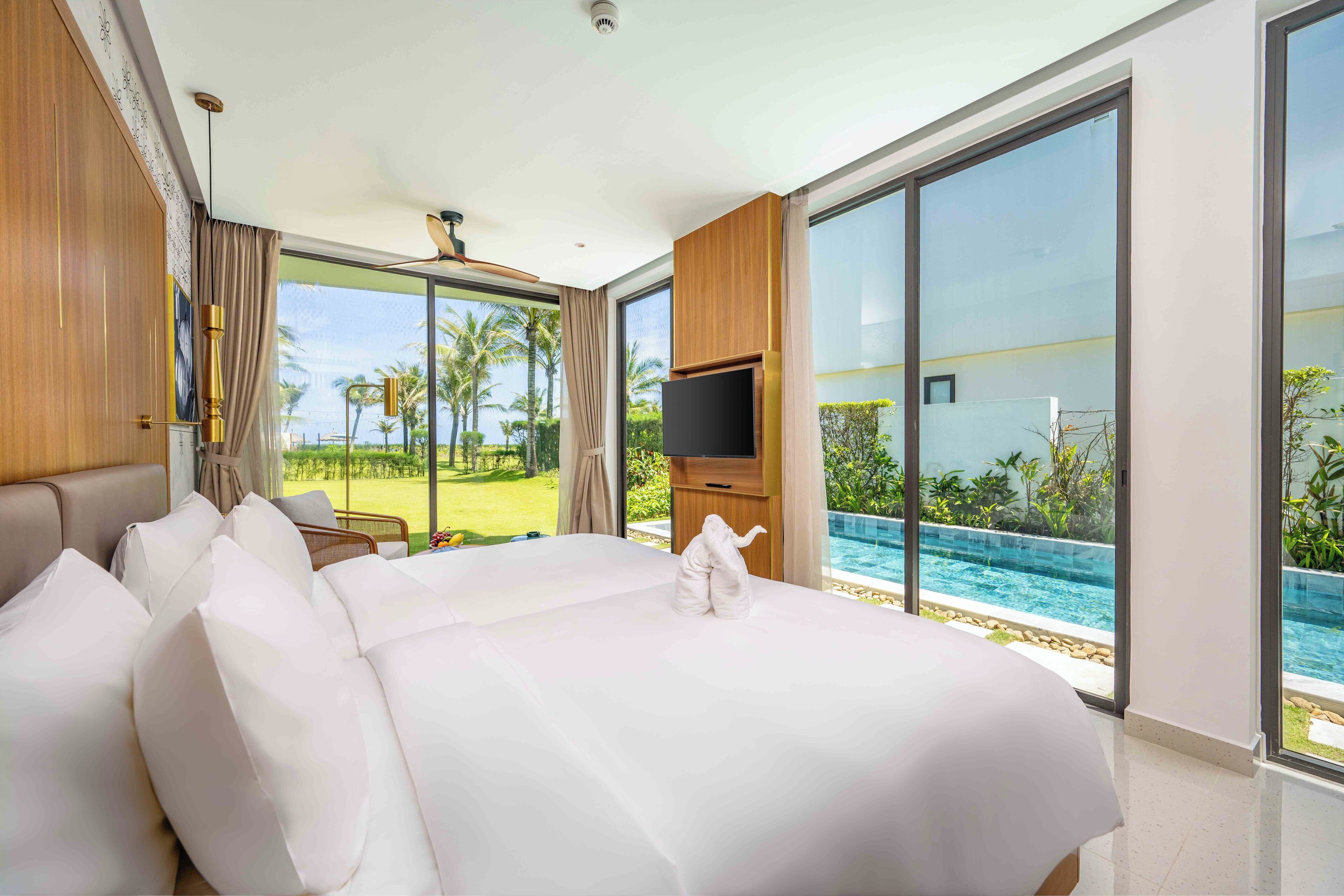 Une chambre d’hôtel moderne dotée d’un grand lit, d’un téléviseur à écran plat et offrant une vue sur une piscine.