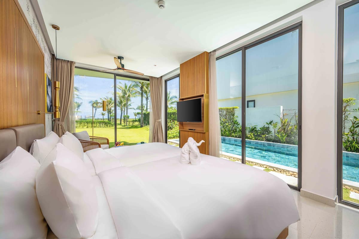 Habitación de hotel moderna con una cama grande, un televisor de pantalla plana y vista a una piscina.