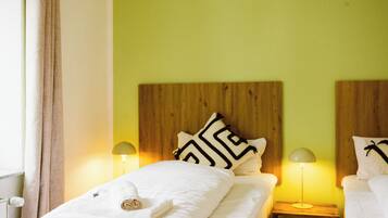 A hotel room with a wooden headboard, two bedside lamps, a bed with white bedding, and a window with curtains.