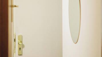 A door with a keyhole and a handle, and a mirror on the wall.