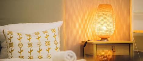 A neatly made bed with a patterned pillow and a bedside table with a textured lamp.