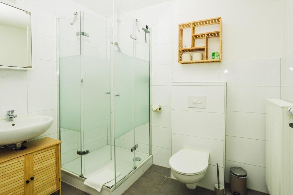 Un bagno moderno con doccia vetrata, un lavandino bianco e un water.