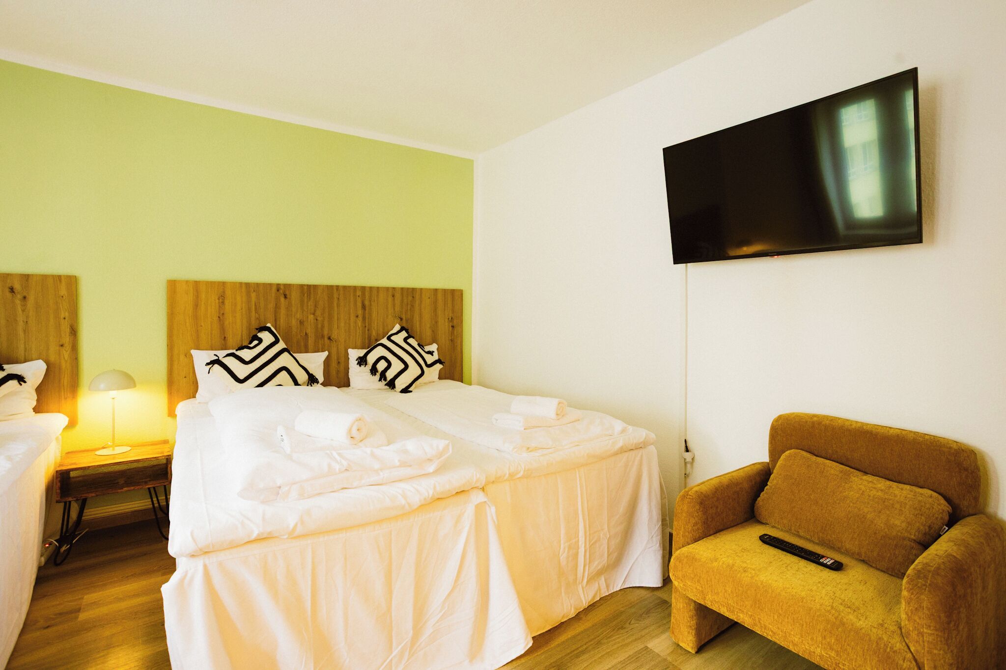 A hotel room with two beds, a TV, and a sofa.