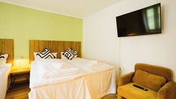 A hotel room with two beds, a TV, and a sofa.