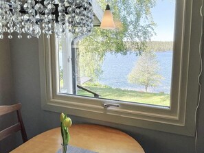 Ein Zimmer mit einem großen Fenster, einem Holztisch und einer Vase mit einer Blume.