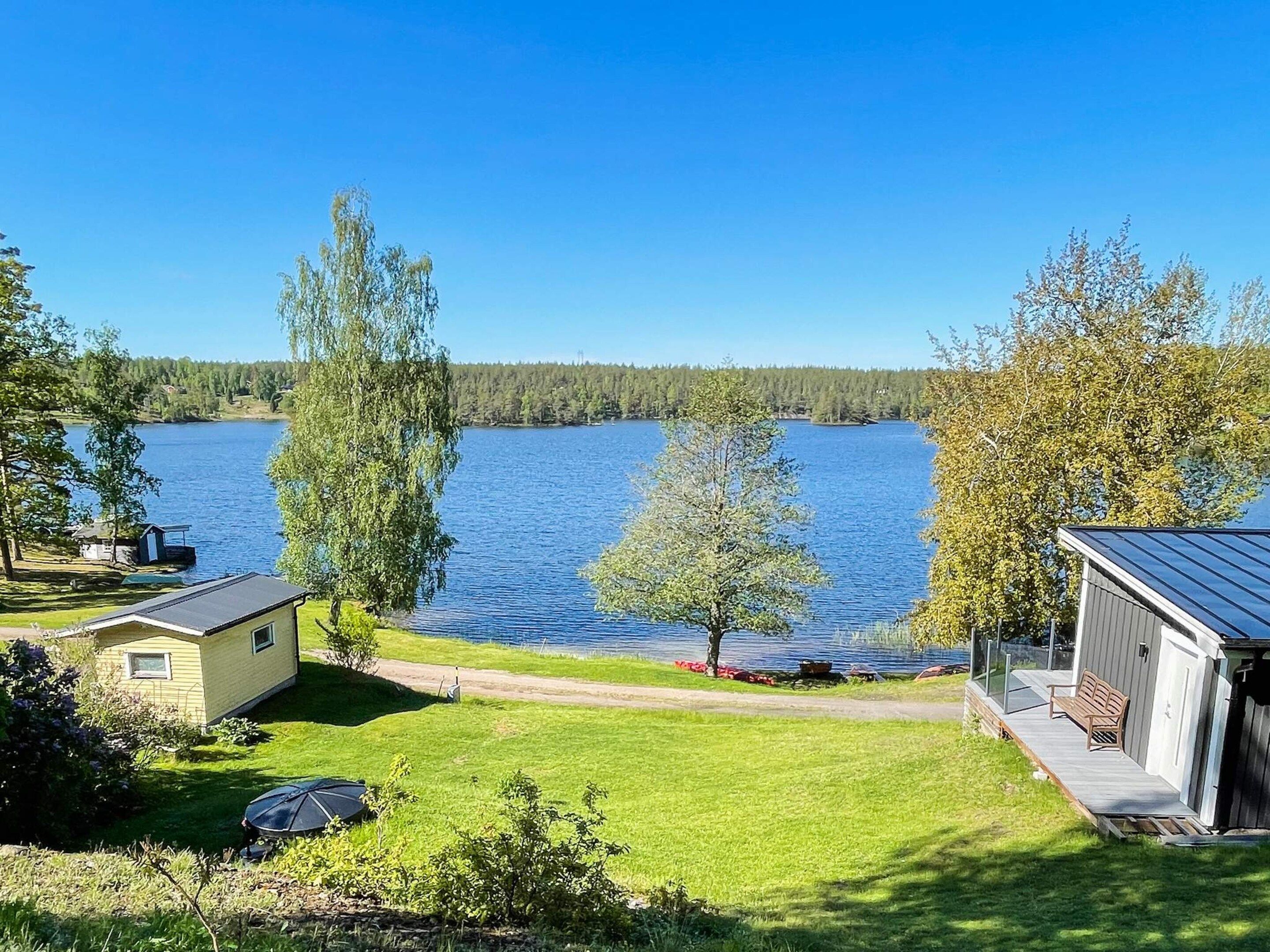 A lakeside property with a small house, a deck, and a clear view of the lake.