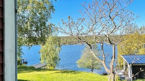 Une vue sur le lac, avec une zone herbeuse, un arbre et un petit bâtiment doté d’un toit.