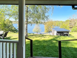 Un espace extérieur abrité, avec vue sur un lac, un petit abri de jardin et une pelouse verdoyante.