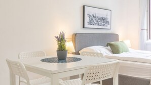 Ett hotellrum med en säng, ett bord med stolar, en krukväxt och en inramad tavla på väggen.