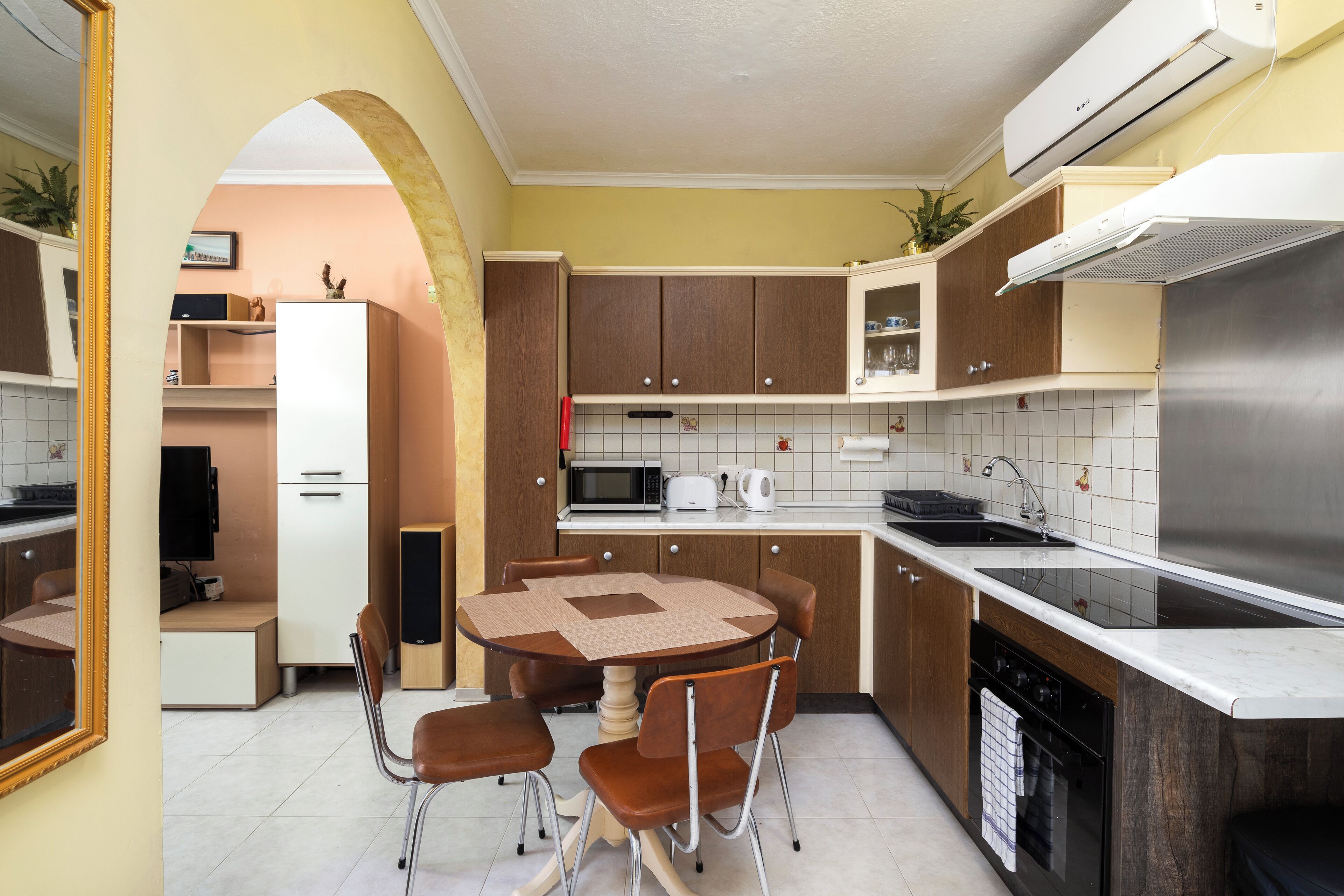 Uma cozinha compacta com área de refeições, com micro-ondas, torradeira e pia de aço inoxidável.