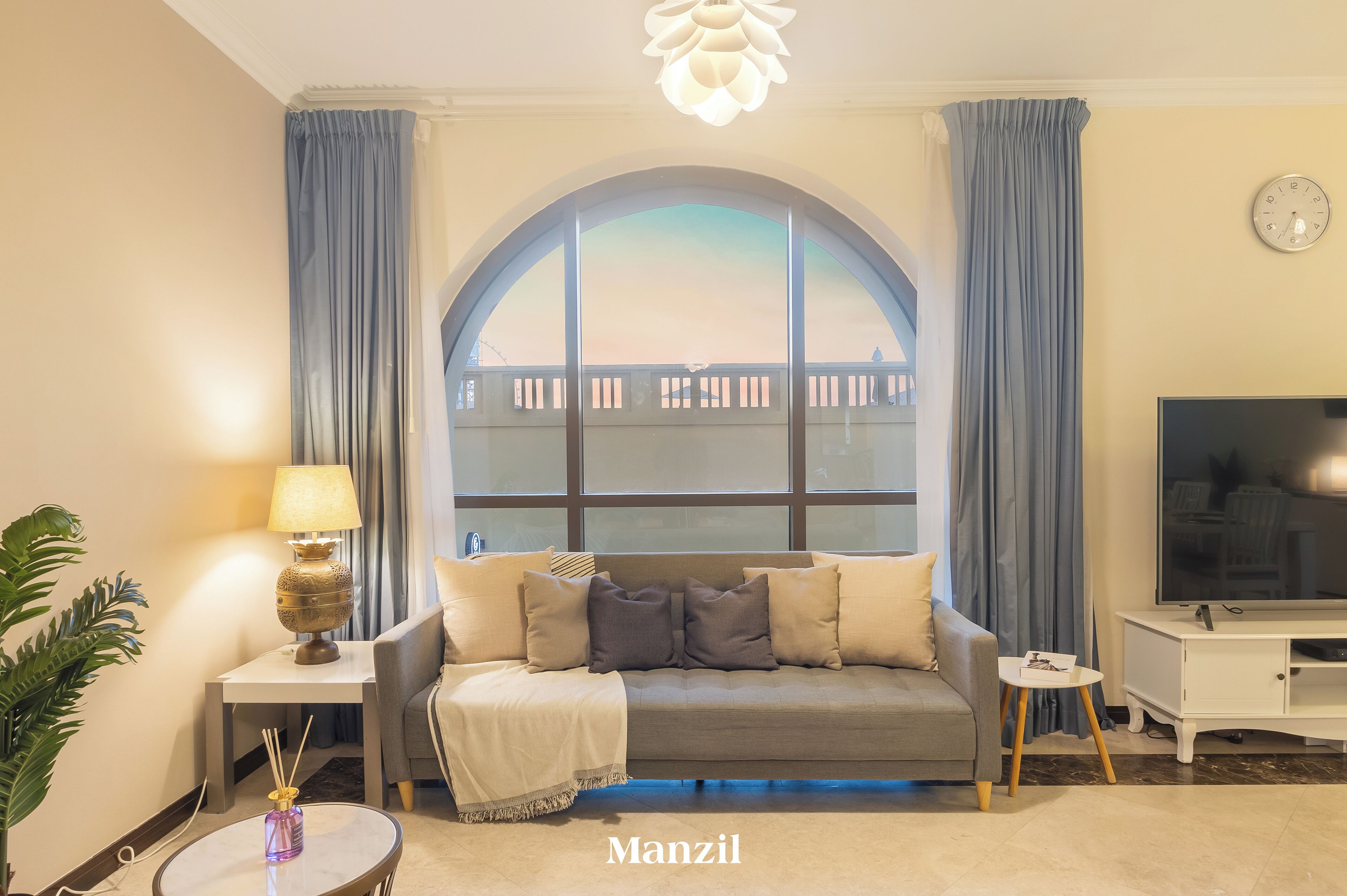 A living room with a sofa, a TV, a lamp, and a view through a large window.