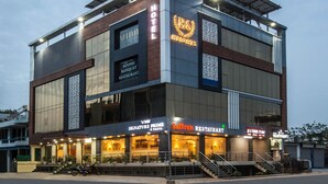 Ένα ξενοδοχείο με μοντέρνο σχεδιασμό, που διαθέτει μια ταράτσα και πινακίδες που υποδεικνύουν την τοποθεσία ενός εστιατορίου και ενός στούντιο.