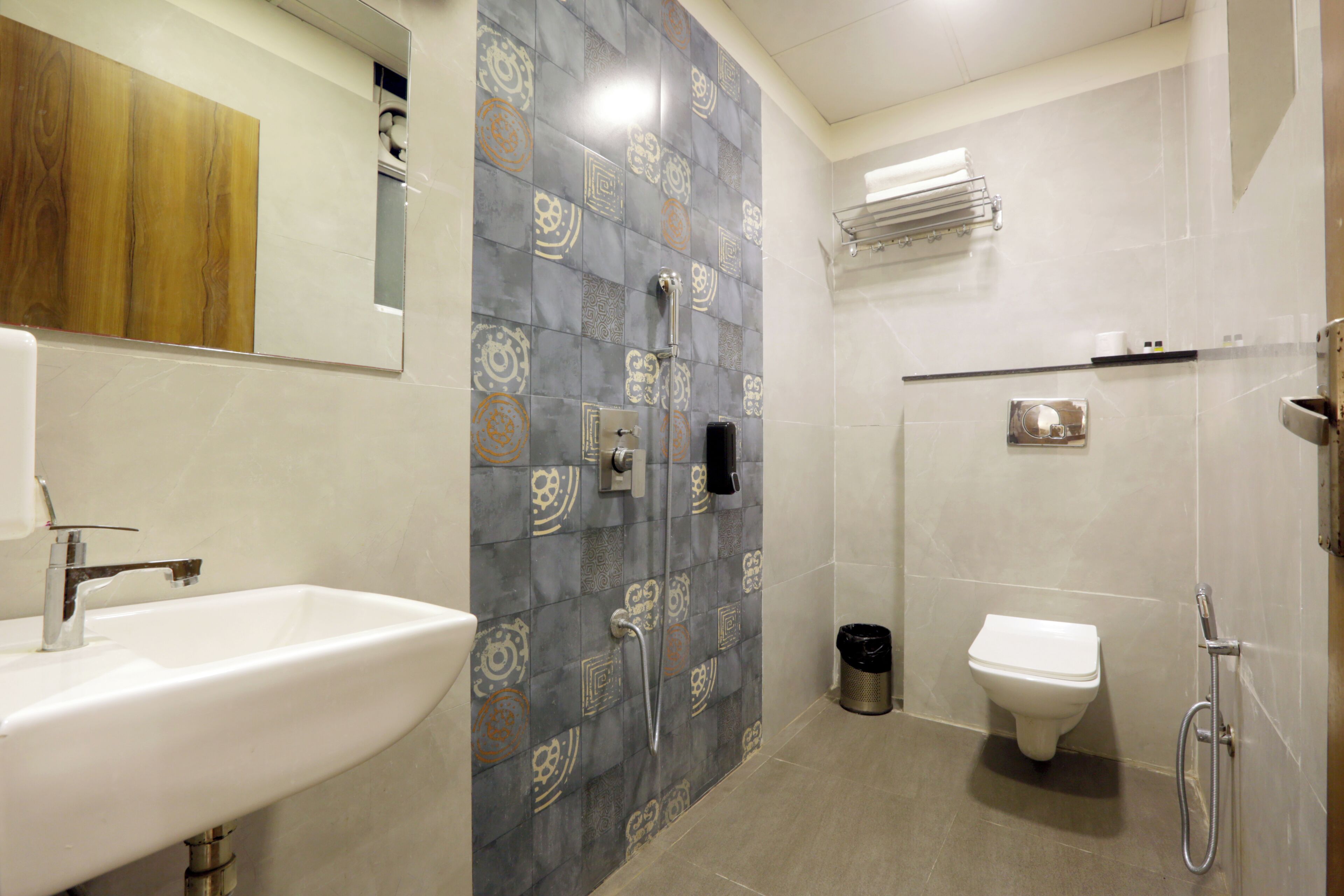 A bathroom with a sink, toilet, shower, and a mirror.