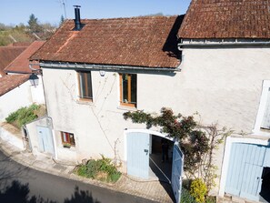 A two-story house with a tiled roof, a blue door, and a small garden area. - Holiday cottage in the Dordogne – Gite la Grange 24, near Perigueux, Brantome (Saint-Martial-d'Albarède)