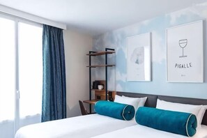 A hotel room with a bed, a desk, and a chair. There are two framed pictures on the wall. - 798 Inn (Dali)