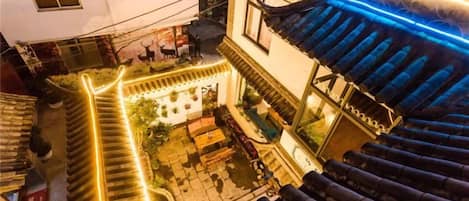 A traditional courtyard with a staircase, a dining area, and a building with a blue-tiled roof.