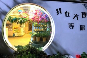 Una ventana circular con vista a un cuarto que contiene plantas en macetas y un letrero con caracteres chinos.