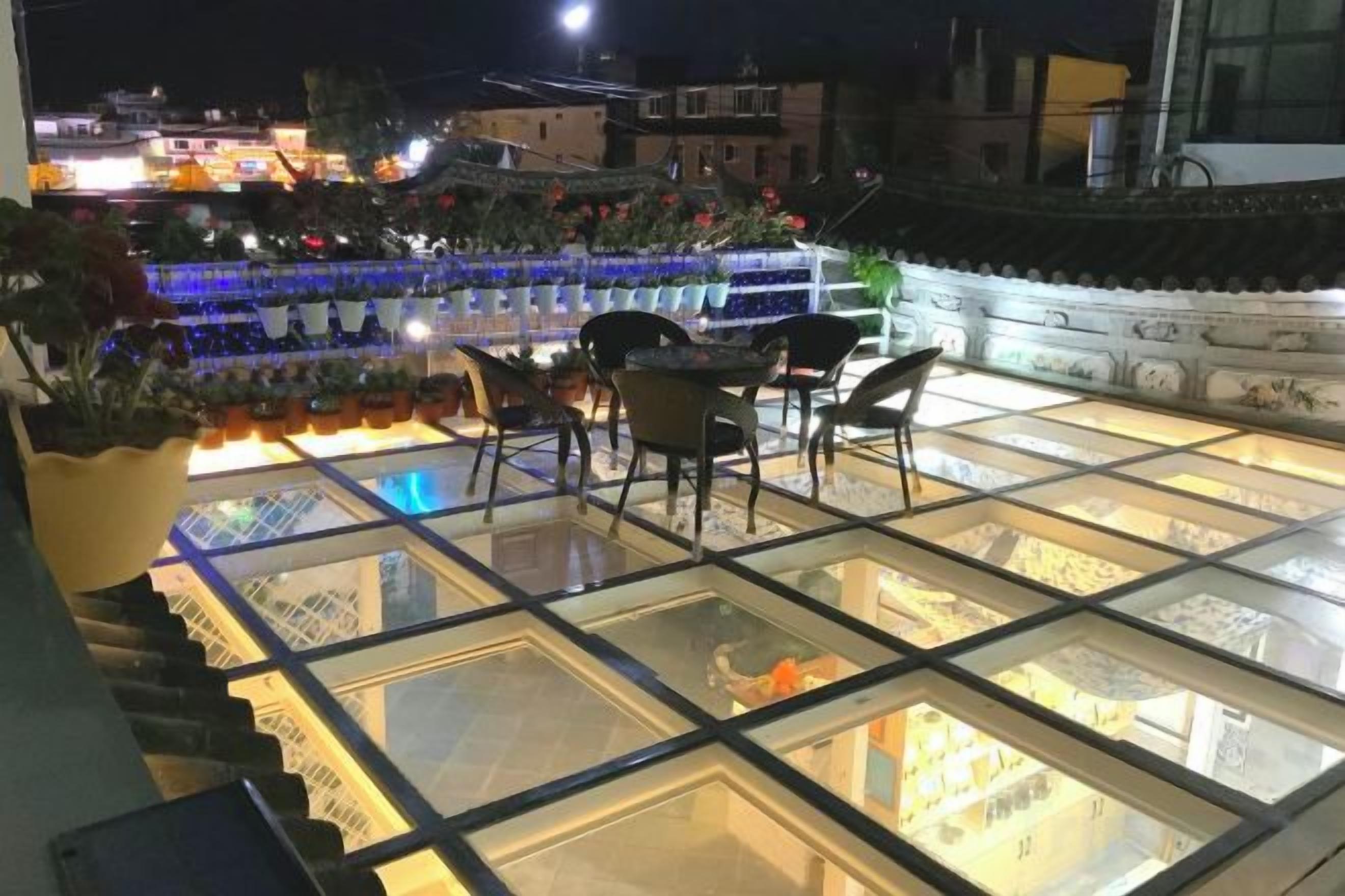 Una terraza en la azotea con piso de vidrio, mobiliario exterior y vistas a la ciudad.