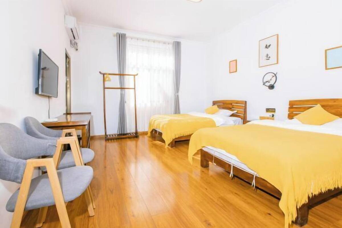 A hotel room with two beds, a desk, a chair, and a TV.