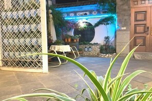 An outdoor patio area with a stone floor, a white table with chairs, and potted plants. - 798 Inn (Dali)