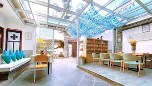 Un espace intérieur vaste, doté d’un plafond haut, d’un coin salon avec des chaises et une table, ainsi que d’une bibliothèque.
