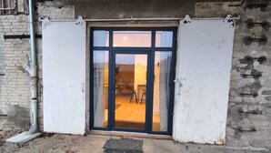 Une porte dotée d’un panneau de verre, qui donne sur un espace intérieur aménagé avec une chaise et une table.