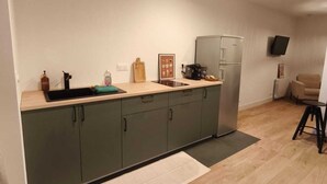 Une cuisine moderne dotée d’un îlot central, de meubles de rangement intégrés et d’un réfrigérateur en acier inoxydable.