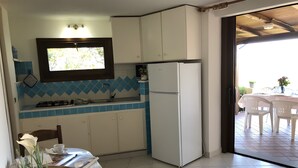 A kitchen with white cabinets, a white refrigerator, a window with a view, and a dining area with a table and chairs.