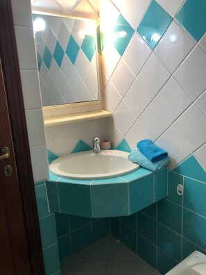 Ein Badezimmer mit einem weißen Waschbecken, einem Spiegel und einem blauen Handtuch auf der Ablagefläche.