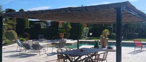 An outdoor patio with a pool, seating, and a pergola.