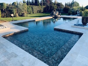 Ein rechteckiger Swimmingpool mit klarem Wasser, umgeben von einer gefliesten Liegefläche.