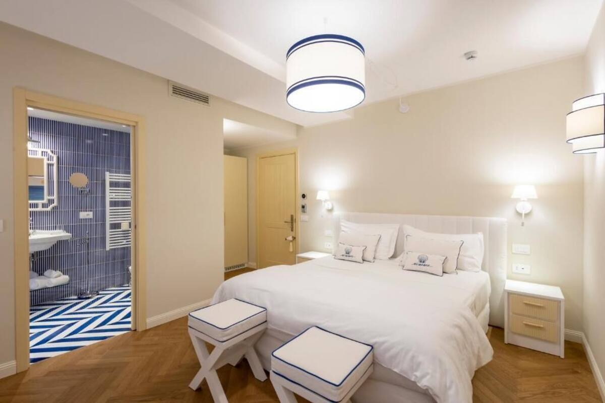 Un dormitorio con una cama grande, mesitas de noche, un armario y un baño visible a través de una puerta.