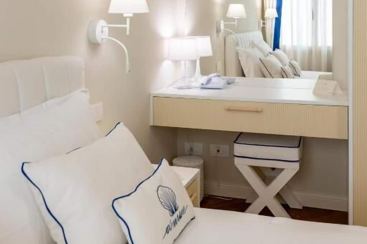 Habitación de hotel con cama, mesita de noche, lámpara y espejo.