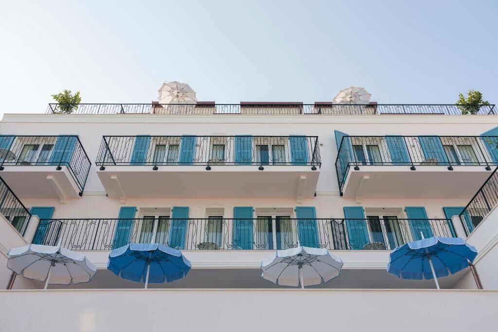 Un edificio de varios pisos con balcones, cada uno con barandilla y un par de sombrillas.