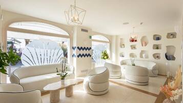 Un salon moderne avec des canapés blancs, une table basse et des objets décoratifs accrochés aux murs.