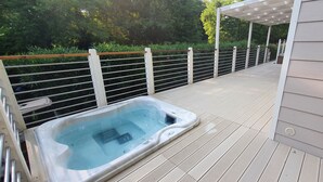 A hot tub on a wooden deck with a metal railing, surrounded by greenery. - Corte Attìlea (Valeggio sul Mincio)