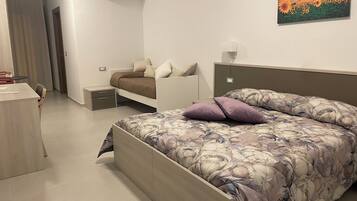 Una camera da letto con un letto, una scrivania, una sedia, un comodino e un condizionatore d'aria a parete.