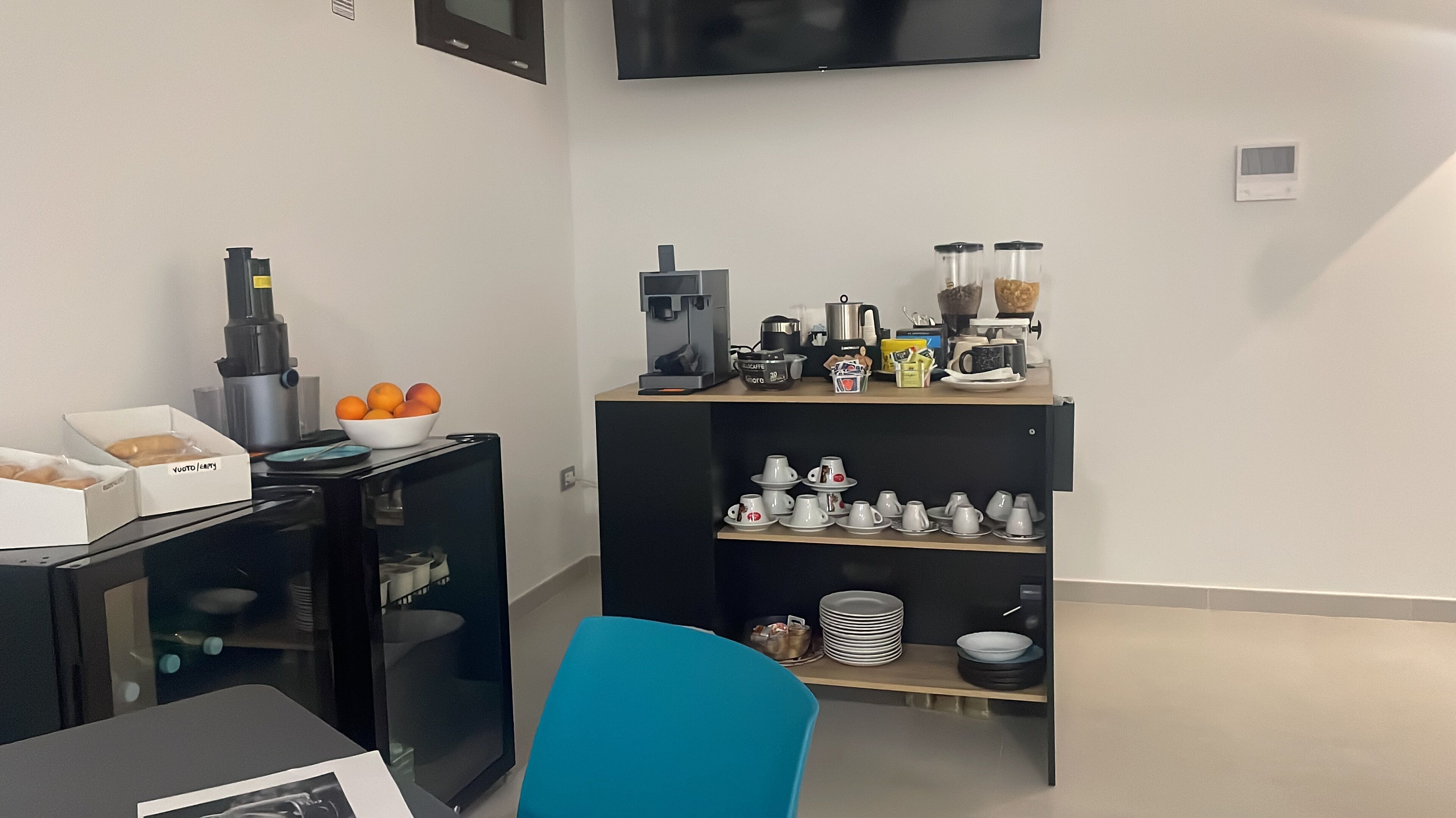 Eine moderne Küche mit einer Kaffeemaschine, einer Orangenschale und einer Auswahl an Tassen und Tellern auf Regalen.