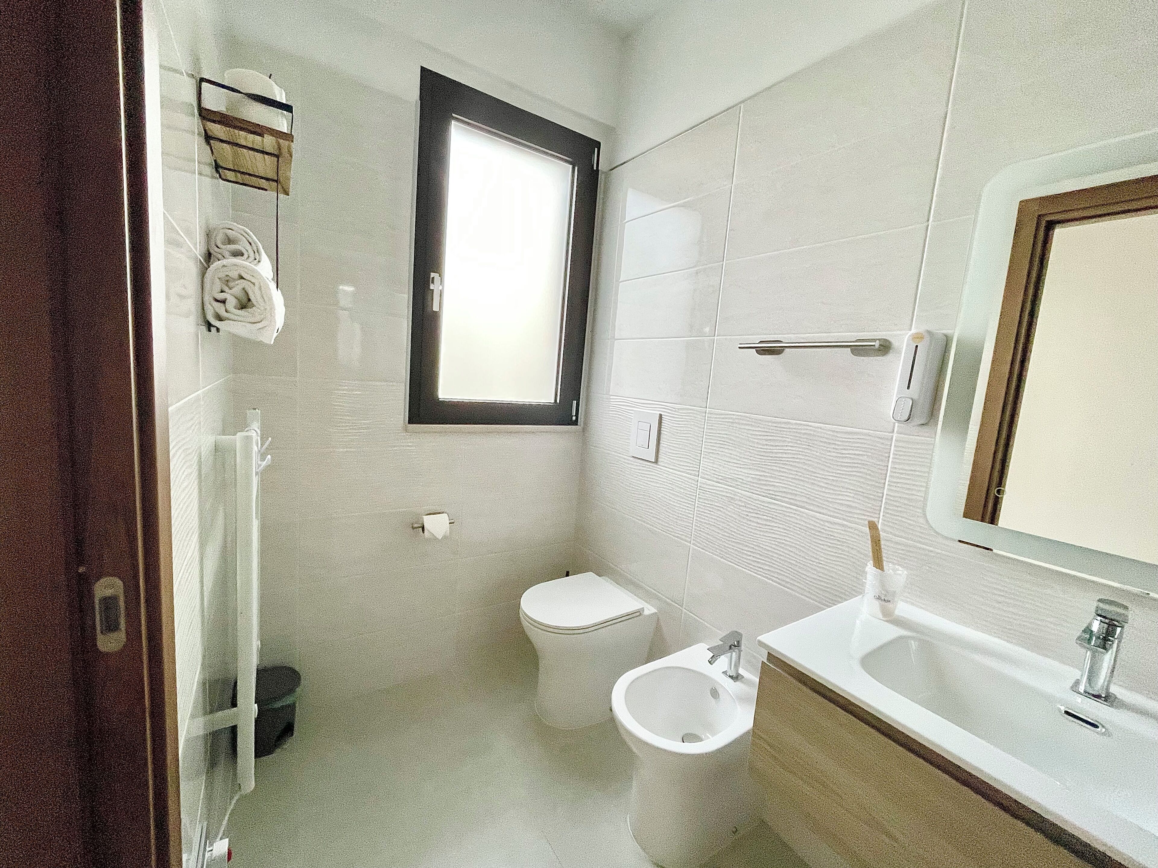 Une salle de bain comprenant des toilettes, un bidet, un lavabo et une fenêtre.