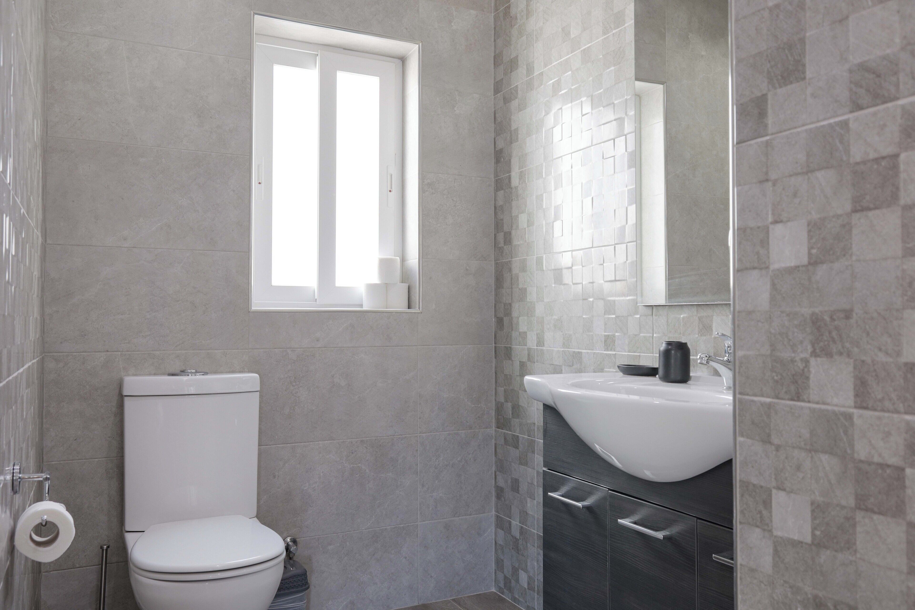 Un baño con inodoro, lavamanos y ventana.