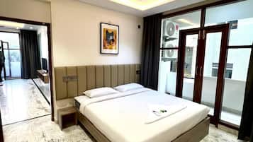 A modern hotel room with a large bed, ceiling fan, and a view through a sliding glass door.