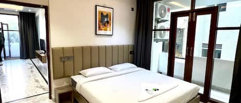 A modern hotel room with a large bed, ceiling fan, and a view through a sliding glass door.
