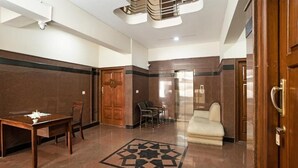 Un hall con una mesa de madera, sillas, un sofá y un suelo estampado.