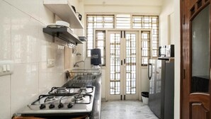 Una cocina con estufa a gas, refrigerador y ventana con vistas.