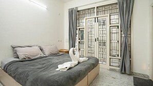 Un dormitorio con cama, cortinas grises y una ventana con rejas.