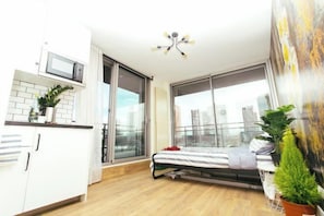 A modern apartment with a kitchenette, a bed with a view, and a balcony with plants. - PARISUHOME (Paris)