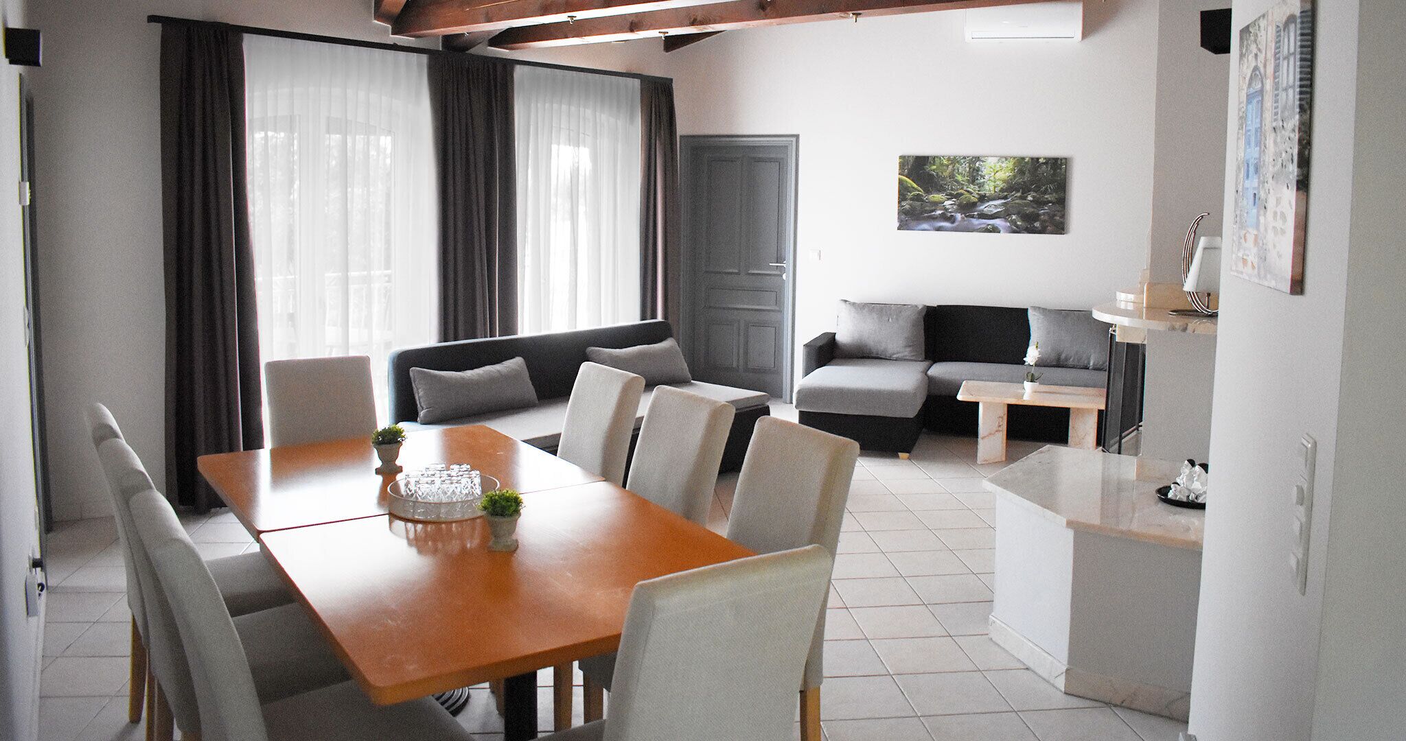 A modern living room with a dining table, sofas, and a small kitchen area.
