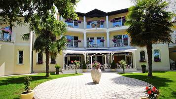 A multi-story hotel with a central courtyard, outdoor seating, and balconies with flowers.