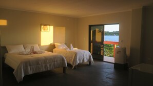 A hotel room with two beds, a small refrigerator, and a view of the sea through a glass door. - Zaru Hotel (Gizo)